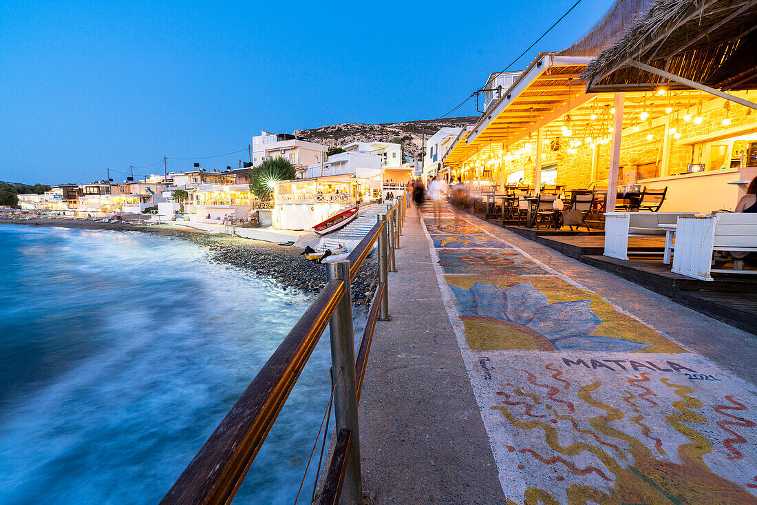 Straßenmalereien auf dem Boden der Matala-Promenade am Meer in der Abenddämmerung, Insel Kreta, Griechenland