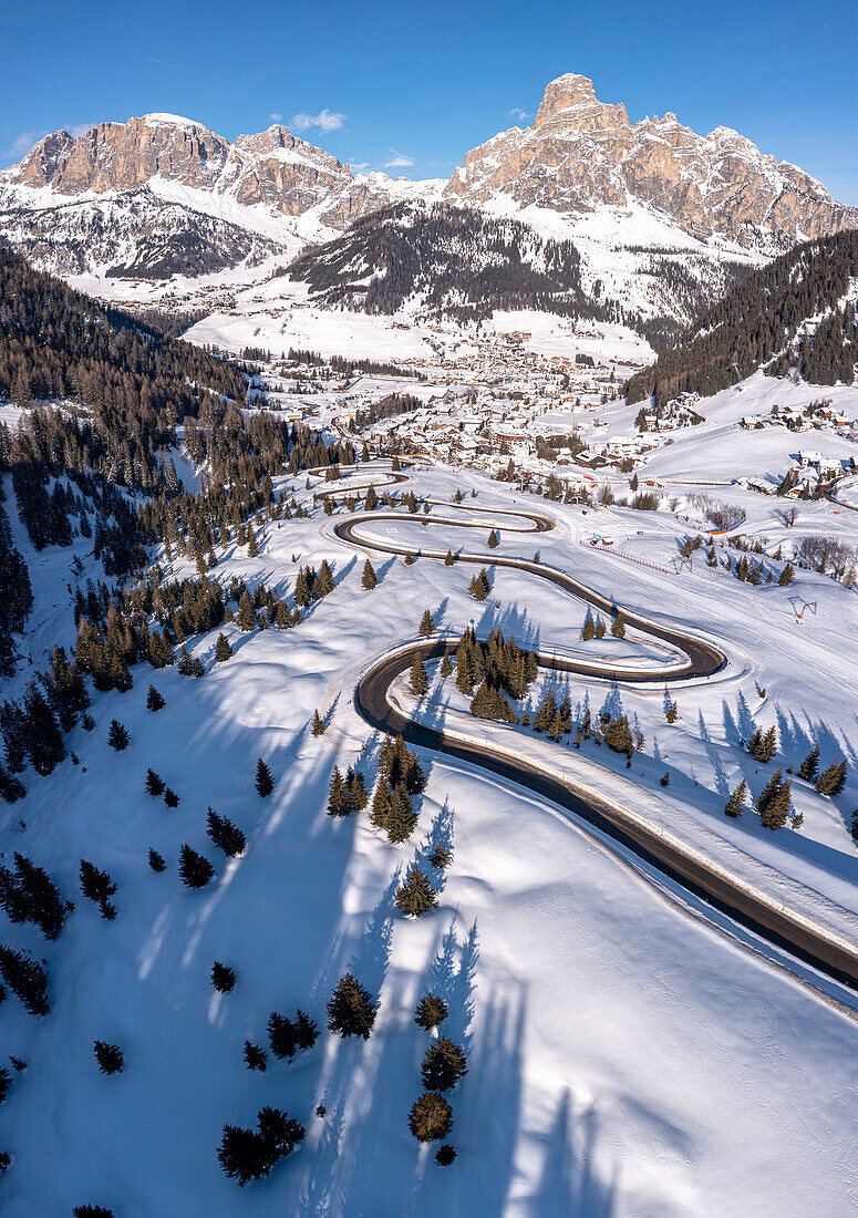 Kurvenreiche Bergstraße im Schnee in Richtung des Bergdorfs Corvara, Gadertal, Dolomiten, Trentino-Südtirol, Italien