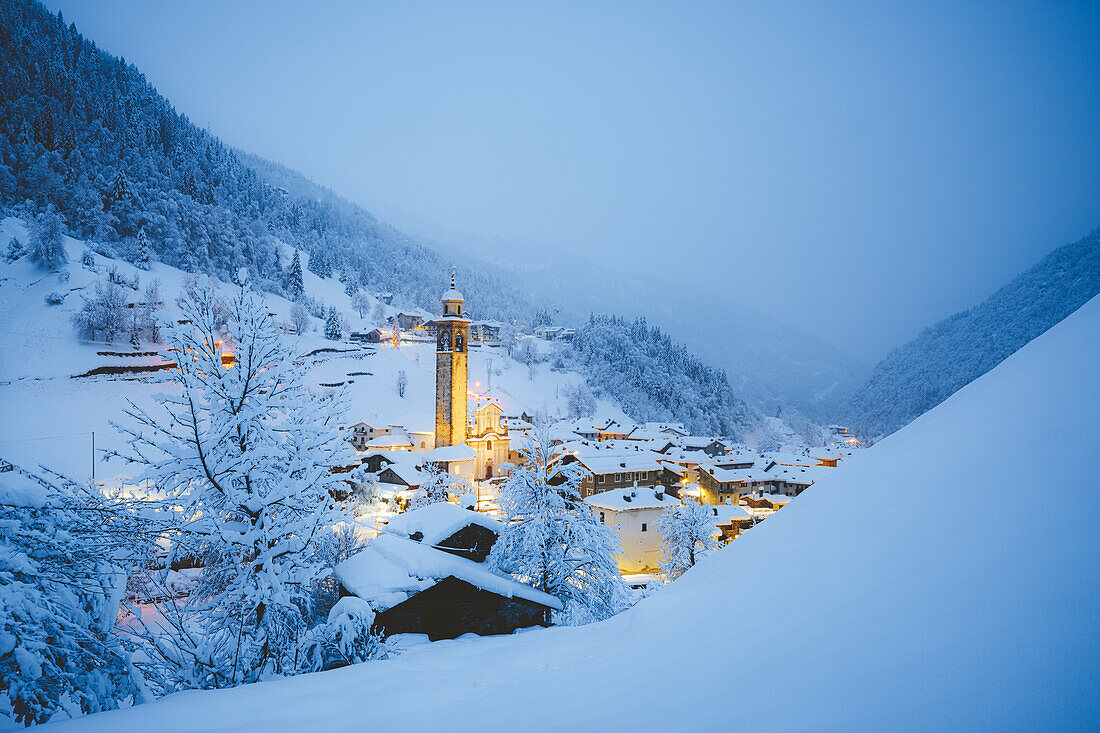 Winter dusk over mountains and village covered with snow, Gerola Alta, Valgerola, Orobie Alps, Valtellina, Lombardy, Italy