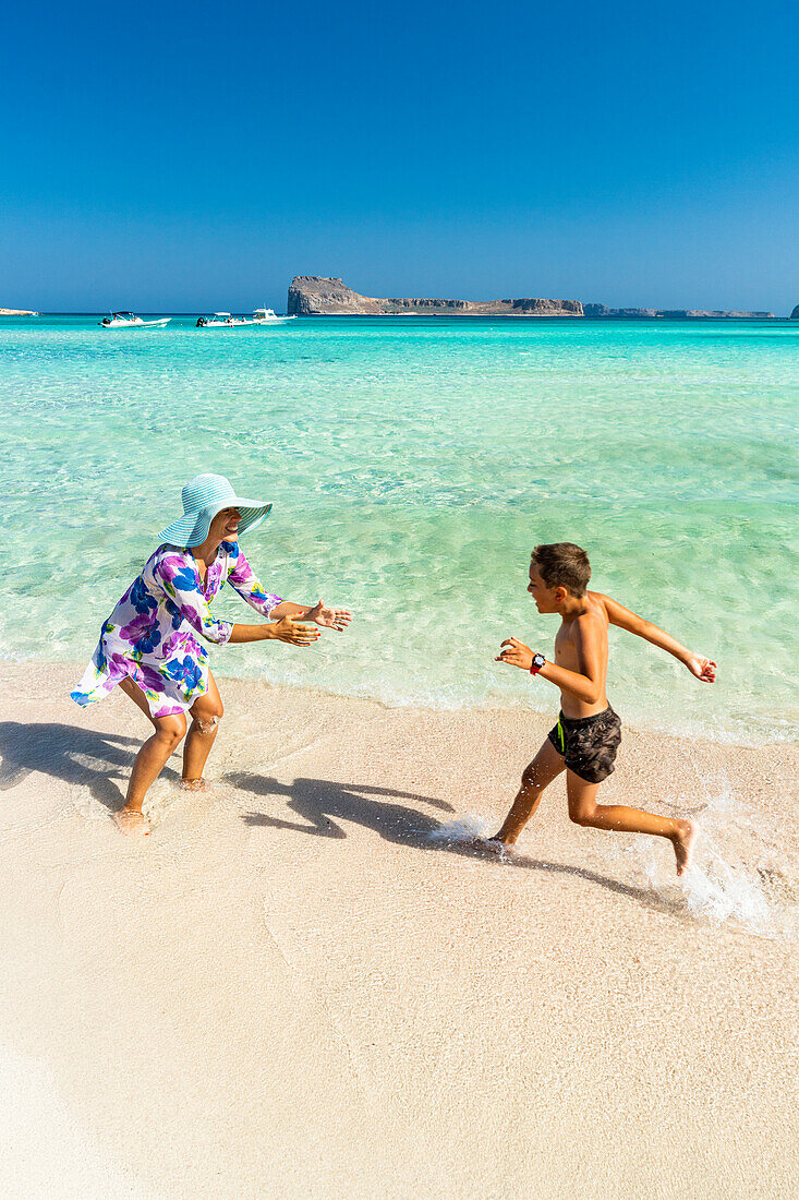 Süßer kleiner Junge, der mit seiner fröhlichen Mutter am Strand Spaß hat, Kreta, Griechenland