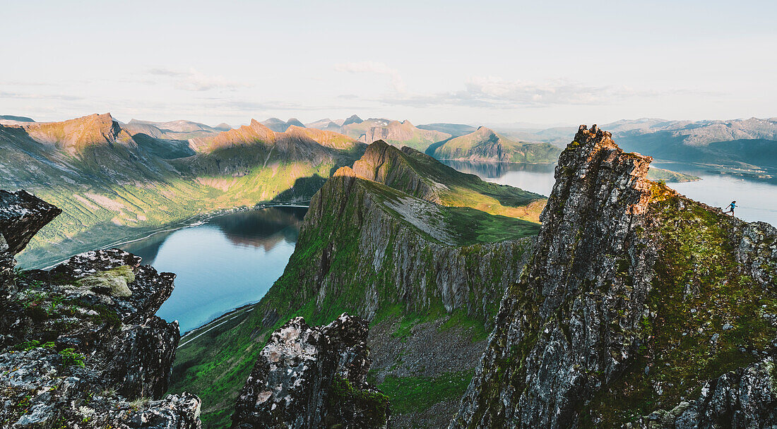 Wanderin, die bei Sonnenuntergang auf einem steilen Bergrücken bergab geht, Insel Senja, Provinz Troms, Norwegen