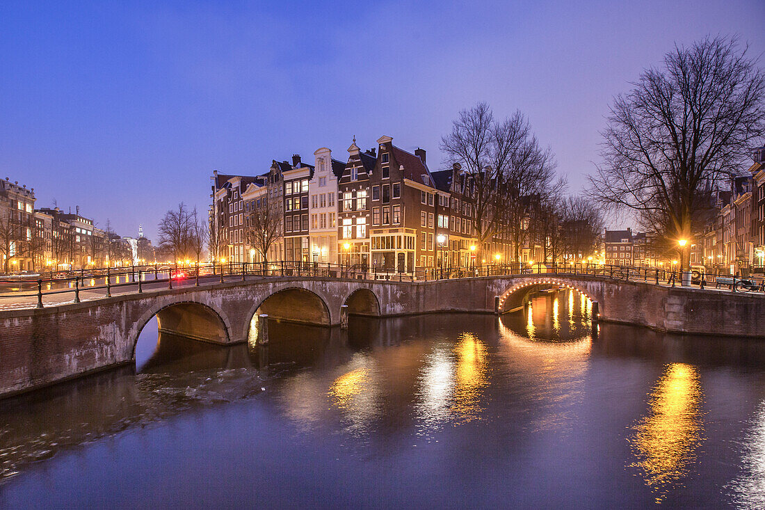 Beleuchtete Gebäude und Brücke spiegeln sich in der Keizersgracht, Amsterdam, Nordholland, Niederlande