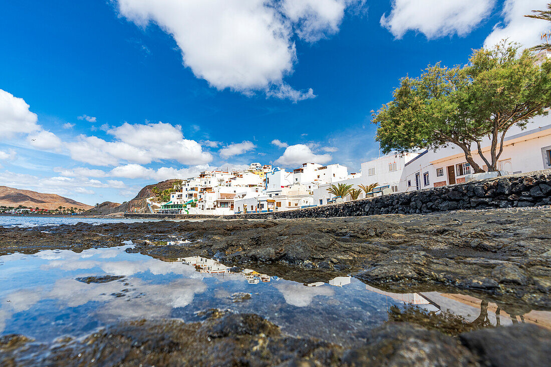Weiß getünchte Gebäude des Küstenortes Las Playitas mit Spiegelung im Meer, Fuerteventura, Kanarische Inseln, Spanien