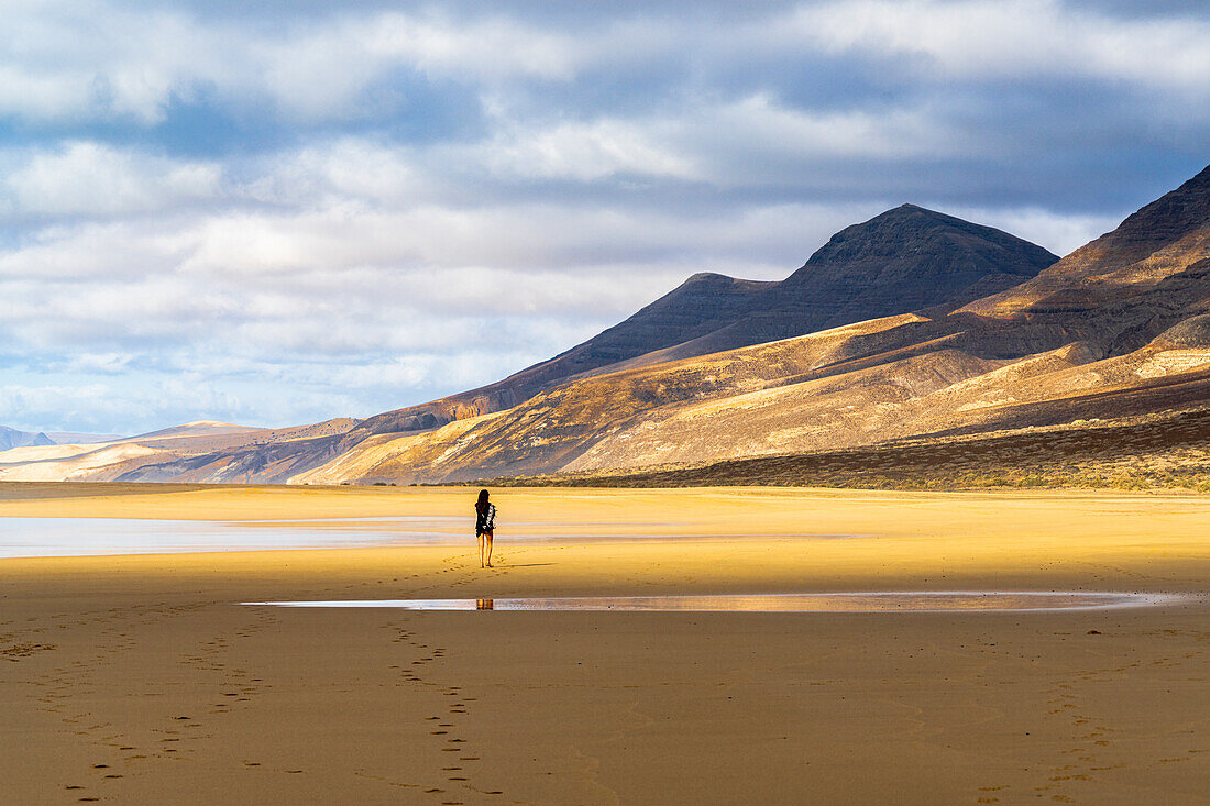 Frau bewundert die Berge vom Cofete-Strand aus, Naturpark Jandia, Fuerteventura, Kanarische Inseln, Spanien