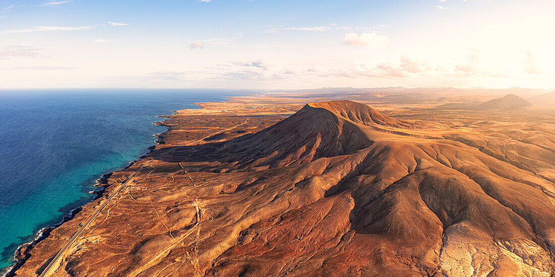 Luftaufnahme des roten Vulkanbergs Montana Roja entlang der Küstenlinie in Richtung Corralejo, Fuerteventura, Kanarische Inseln, Spanien