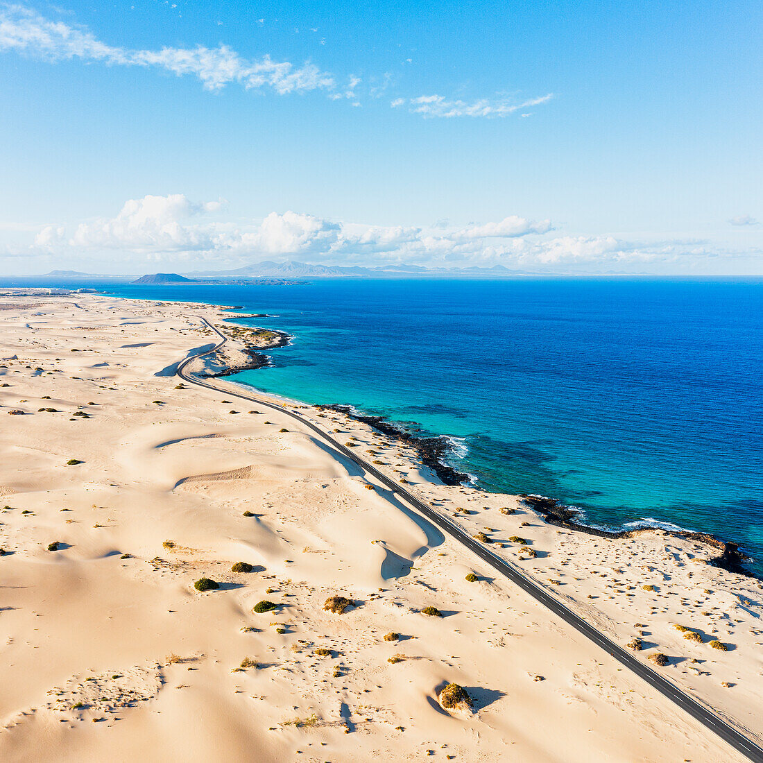 Luftaufnahme einer malerischen Küstenstraße, die durch die Sanddünen des Corralejo-Naturparks führt, Fuerteventura, Kanarische Inseln, Spanien