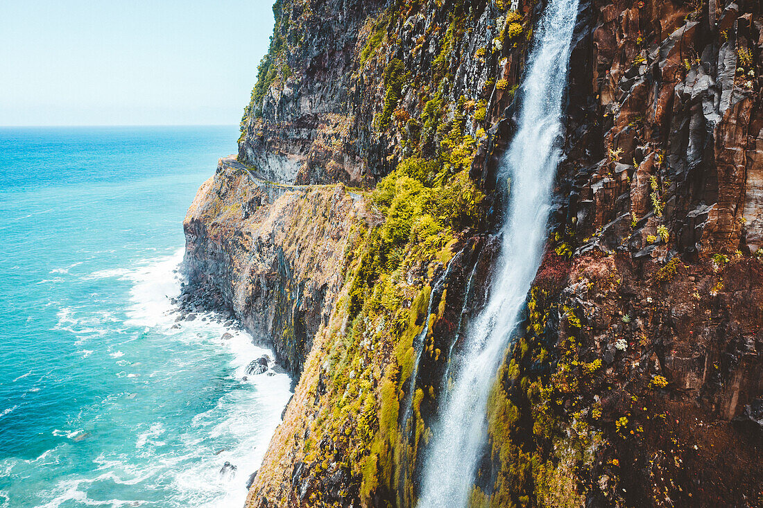 Flowing water of Bridal Veil Fall jumping from cliffs down to ocean, Seixal, Madeira island, Portugal