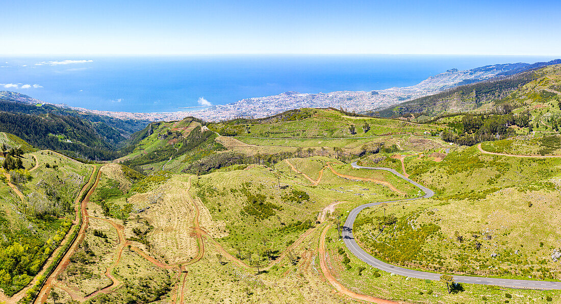 Winding road across the green valley connecting Funchal town to Pico do Arieiro mountain, Madeira island, Portugal