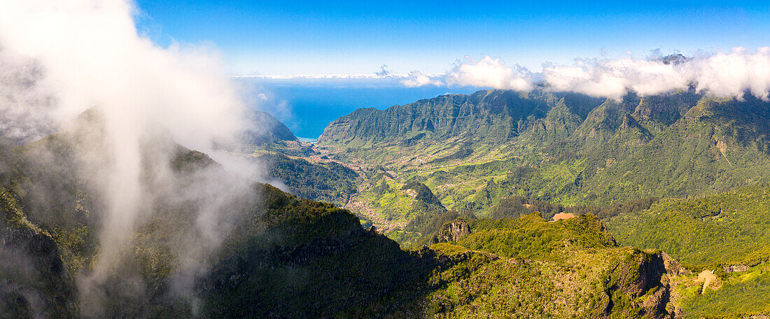 Wolken über Bergen und grünem Tal mit dem blauen Atlantik im Hintergrund, Sao Vicente, Insel Madeira, Portugal