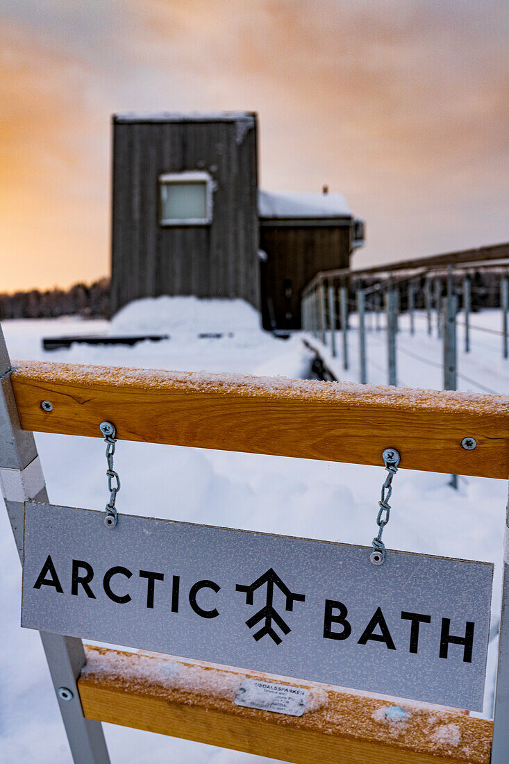 Gefrorenes Plakat des Arctic Bath Spa Hotels in der Schneelandschaft bei Sonnenaufgang, Harads, Lappland, Schweden