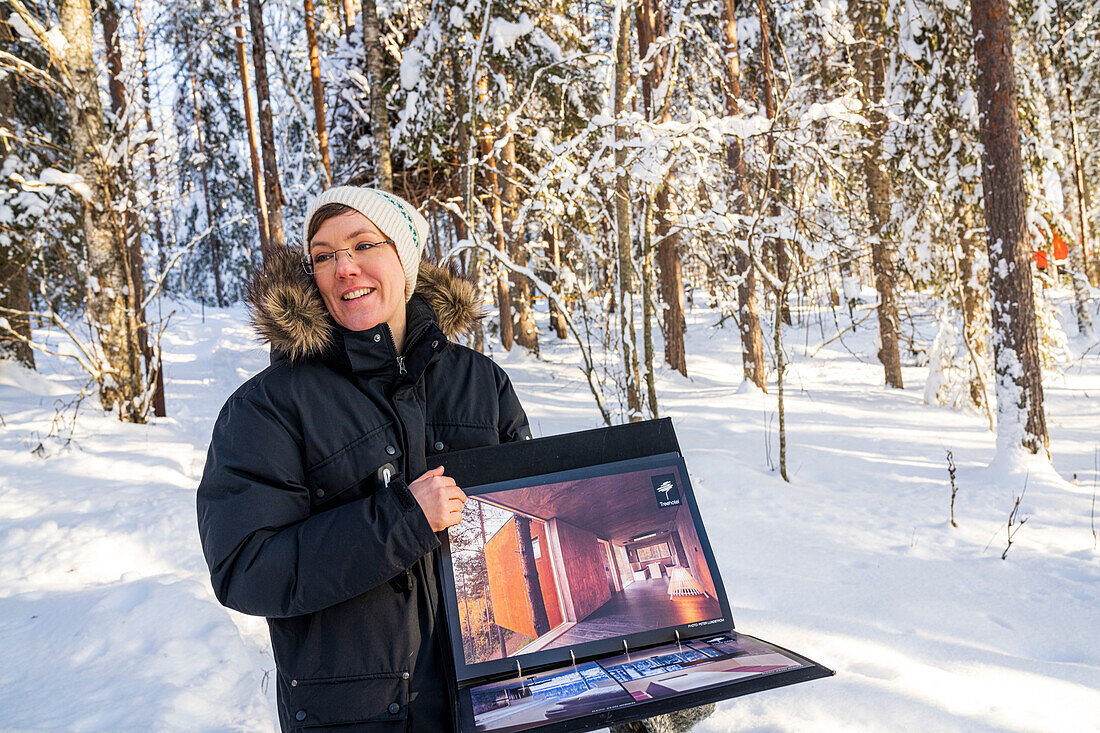 Frau zeigt den Bildband mit den umweltfreundlichen Zimmern des Tree Hotel, Harads, Lappland, Schweden