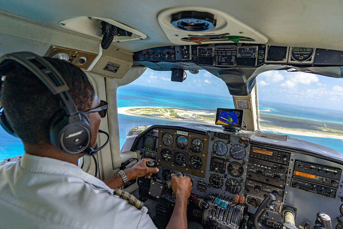 Pilot im Cockpit eines kleinen zweimotorigen Privatflugzeugs beim Überfliegen der tropischen Insel Antigua, Leeward Islands, Karibik