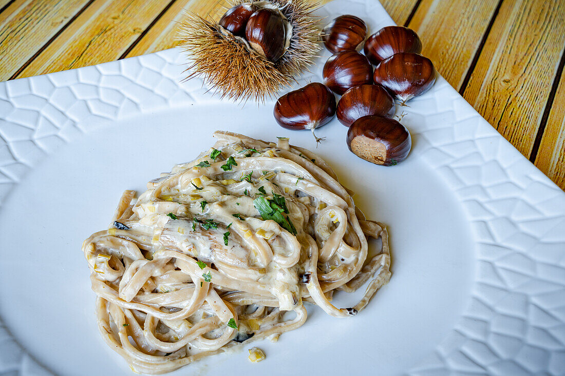 Tagliatelle with cream and chestnuts garnsihed with herbs, Italy