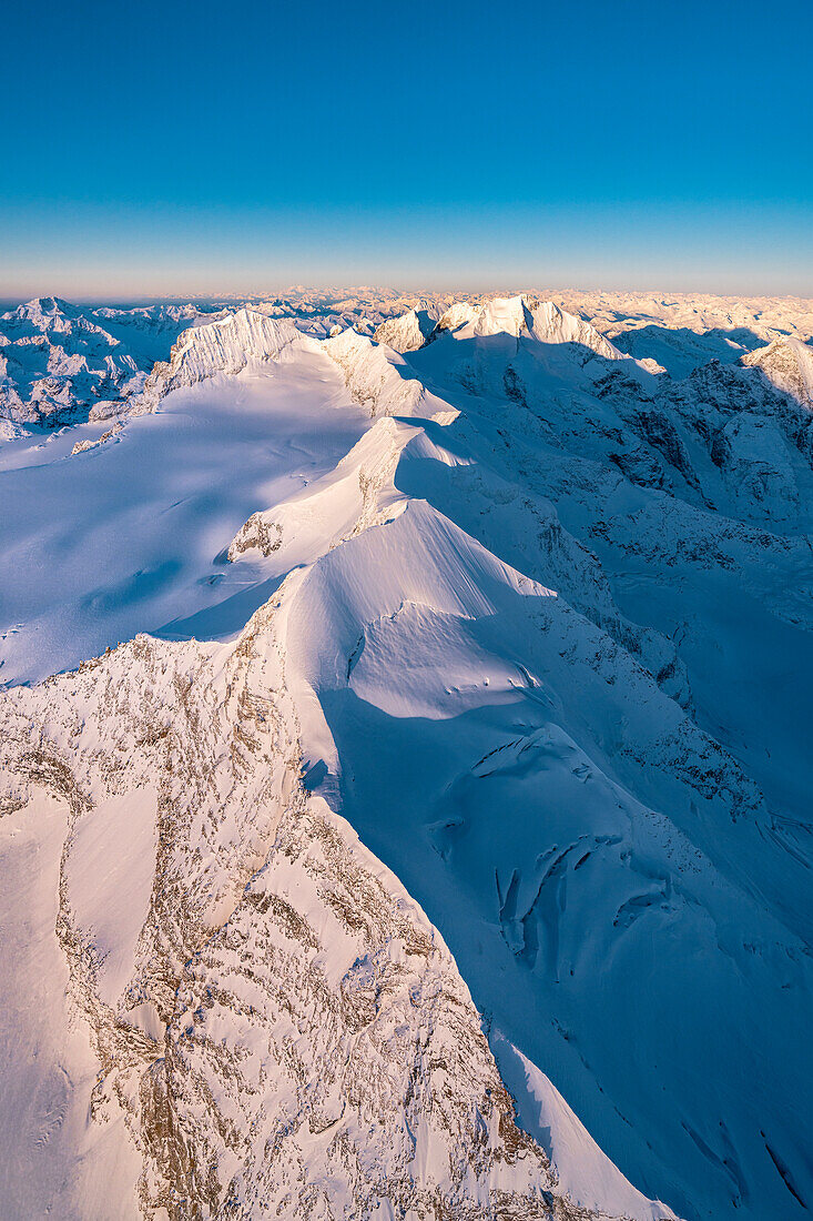 Dramatischer Himmel bei Sonnenaufgang über den schneebedeckten Bergen Piz Palu, Piz Zupo und Piz Bernina, Graubünden, Engadin, Schweiz