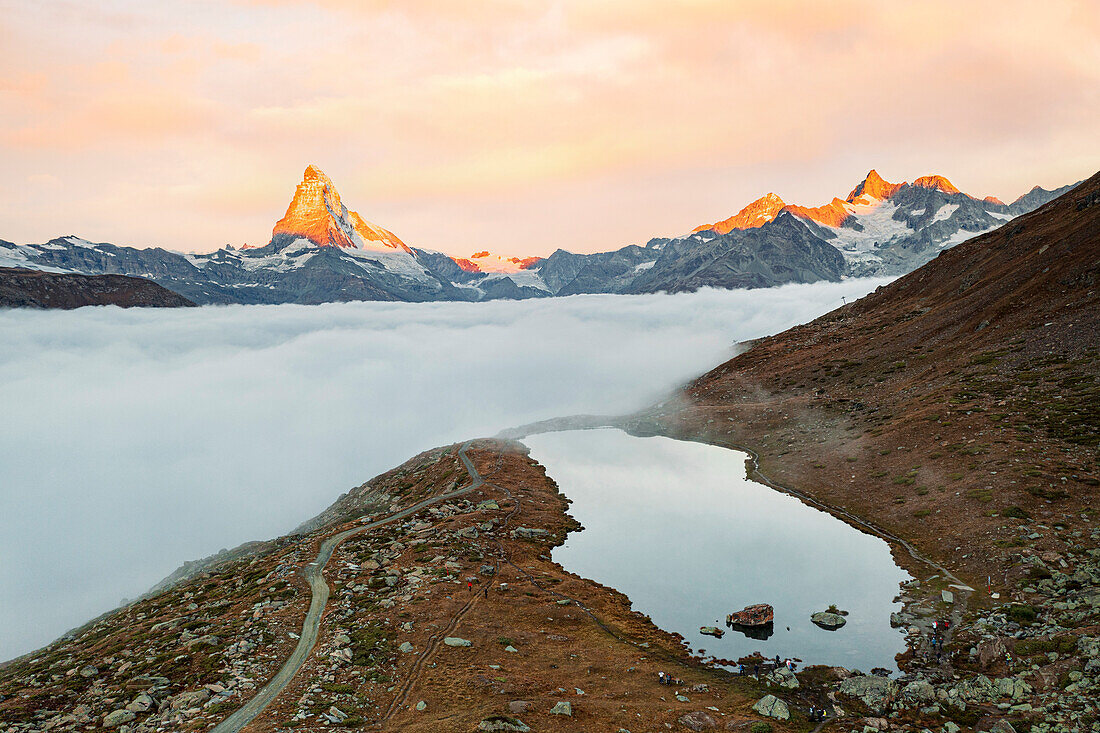 Luftaufnahme des majestätischen Matterhorns und des Stellisees in einem Wolkenmeer bei Sonnenaufgang, Zermatt, Kanton Wallis, Schweiz