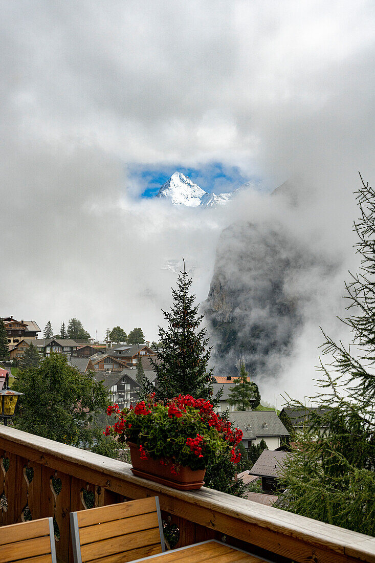 Blick vom Balkon eines Holzchalets auf die aus dem Nebel auftauchende Eiger-Schneespitze, Murren, Jungfrau Region, Kanton Bern, Schweiz