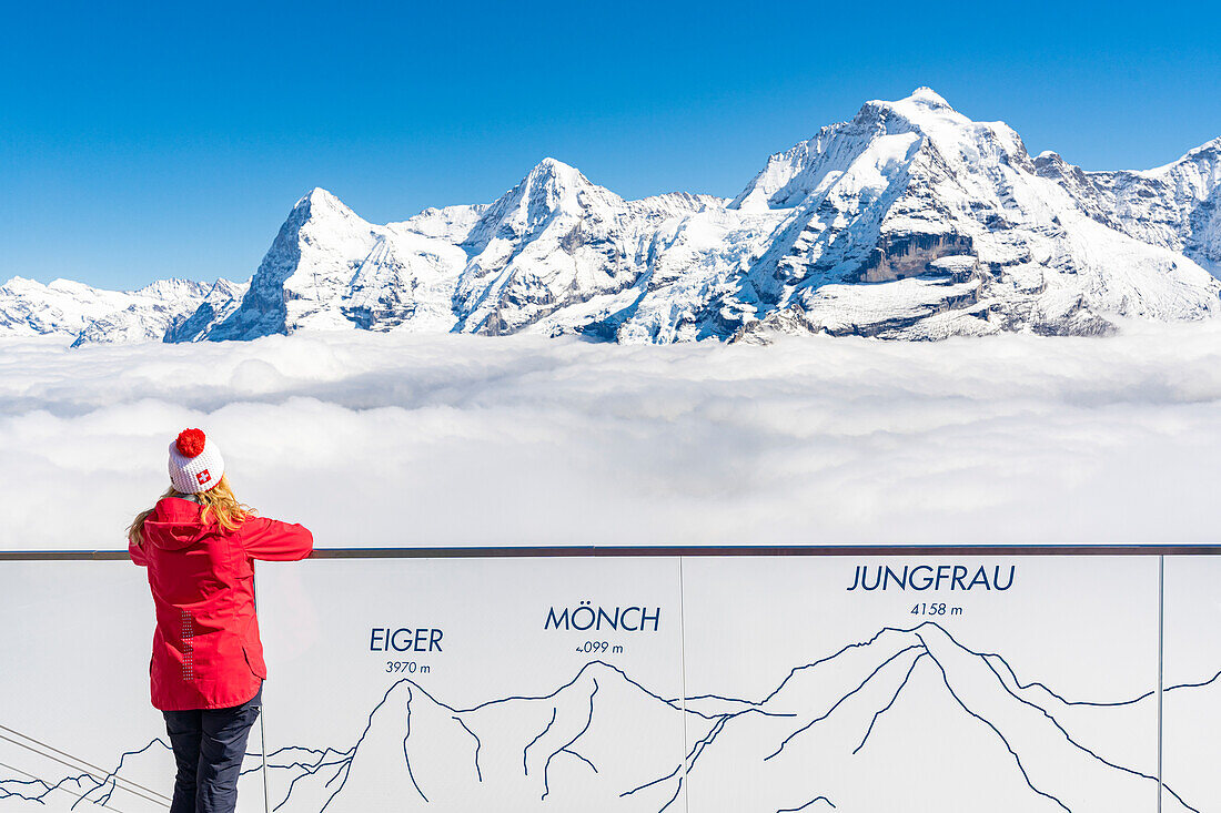 Frau betrachtet die verschneiten Gipfel von Eiger, Mönch und Jungfrau von einem Aussichtspunkt, Murren Birg, Bern, Schweiz