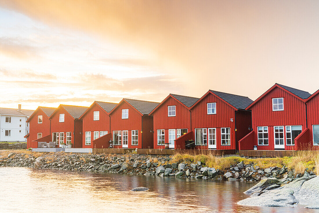 Sonnenaufgang über den kultigen roten Rorbu-Hütten am Meer, Ballstad, Vestvagoy, Nordland, Lofoten, Norwegen