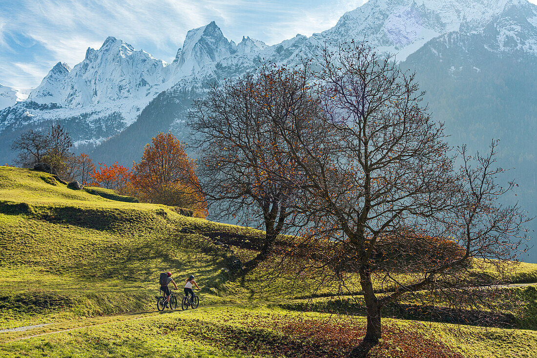 Zwei Personen auf Mountainbikes in der Herbstlandschaft des Val Bondasca am Fusse des Sciore-Gebirges, Graubünden, Schweiz