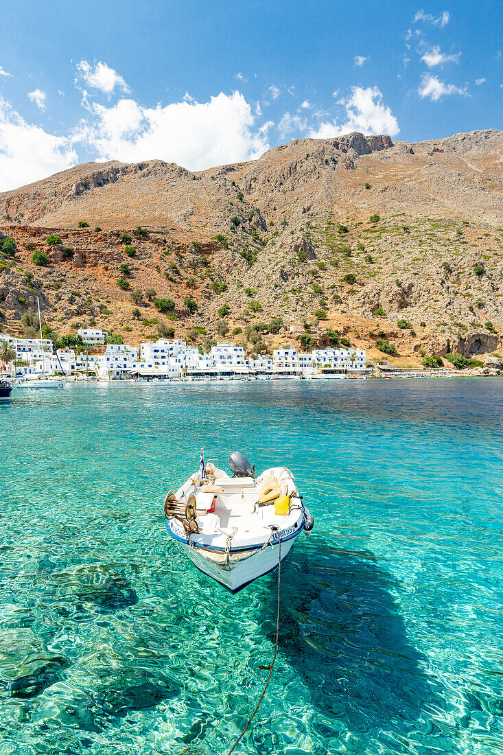 Ein Boot im kristallklaren Meer, das das traditionelle Dorf Loutro umgibt, Insel Kreta, Griechenland