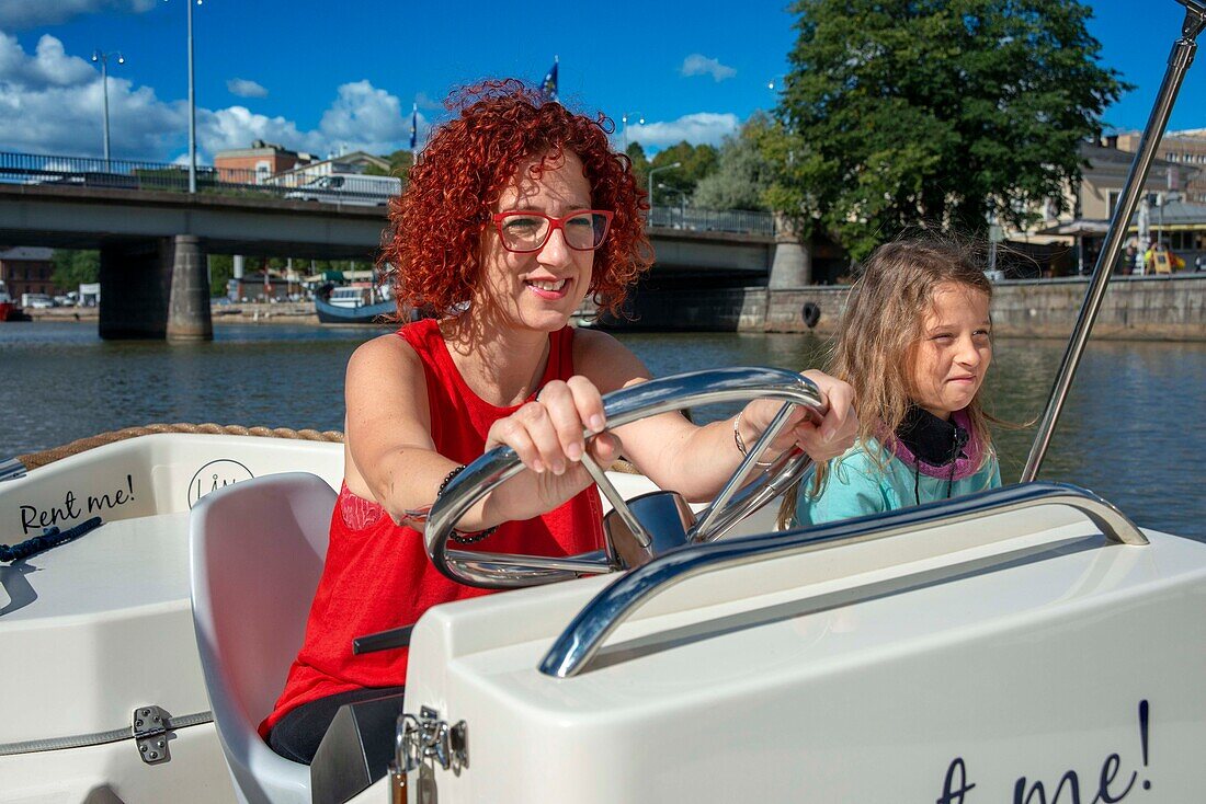 Familie in elektrischen Mietbooten auf dem Fluss Aura in Turku, Finnland.