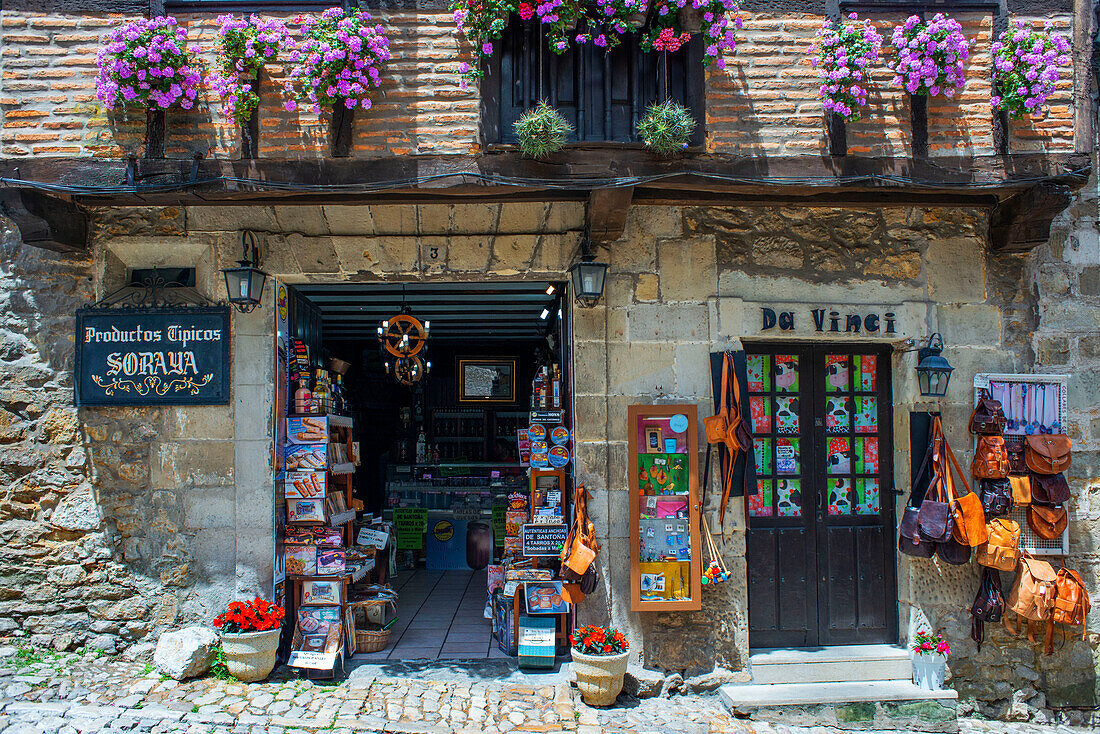 Typische Produkte und Souvenirs entlang der gepflasterten Straße Calle Del Canton in Santillana del Mar, Kantabrien, Nordspanien