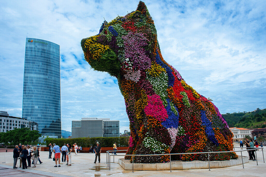 Jeff Koons' sculpture Puppy outside the Guggenheim Museum, Bilbao, Spain. Entrance of of Bilbao Guggenheim Museum reflected in Nervion River, Bilbao, Basque Country, Spain