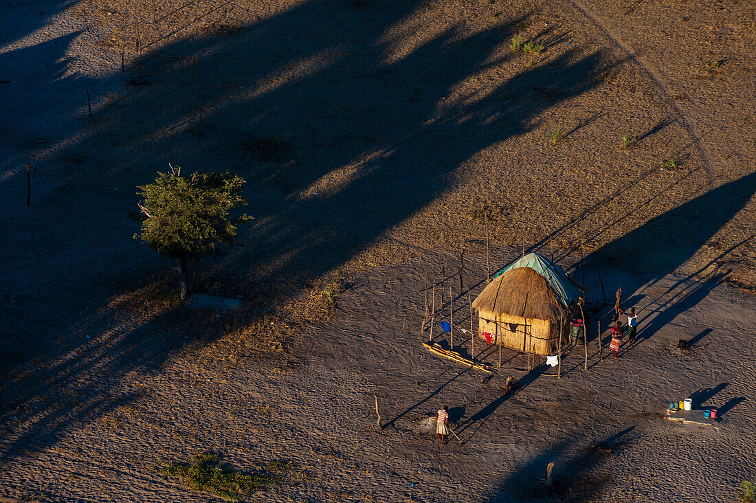 Luftaufnahme eines traditionellen Hauses mit Strohdach. Menschen arbeiten im Hof. Maun, Okavango-Delta, Botsuana.