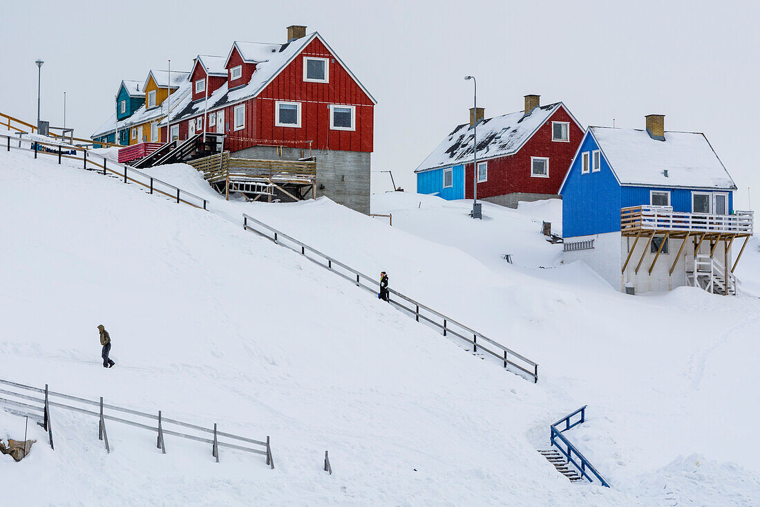 Eine Treppe zu bunten Häusern in einer verschneiten Landschaft. Ilulissat, Grönland.