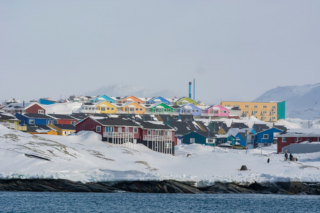 Colorful houses by the sea, in a snowy landscape. Disko Bay, Ilulissat, Greenland.