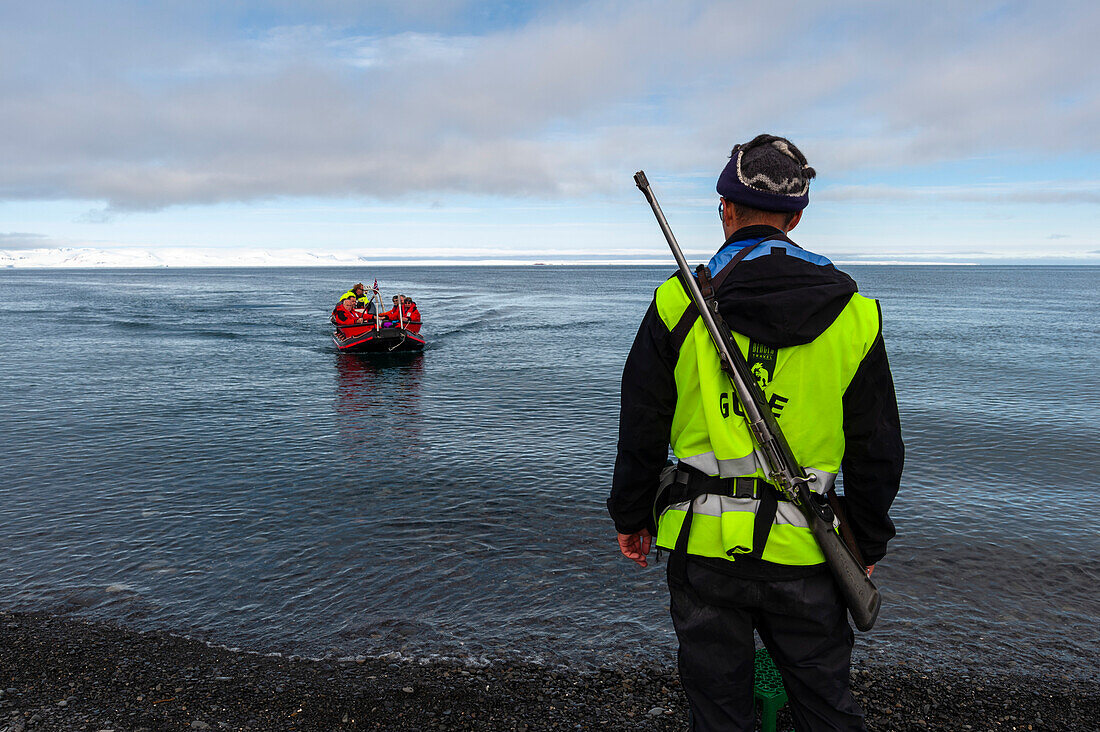 Ein bewaffneter Führer wartet am Ufer von Mushamna auf die Kreuzfahrttouristen. Insel Spitzbergen, Svalbard, Norwegen.