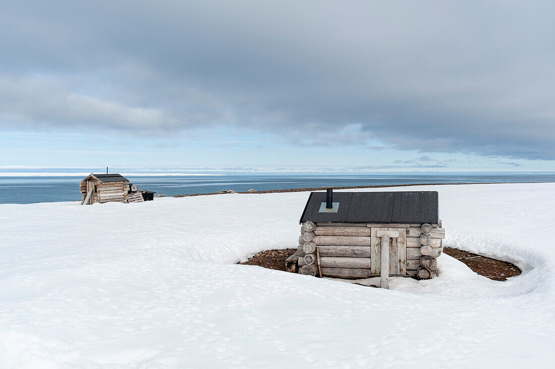 Fuchsjagd-Blockhütten am schneebedeckten Strand von Mushamna. Mushamna, Insel Spitzbergen, Svalbard, Norwegen.