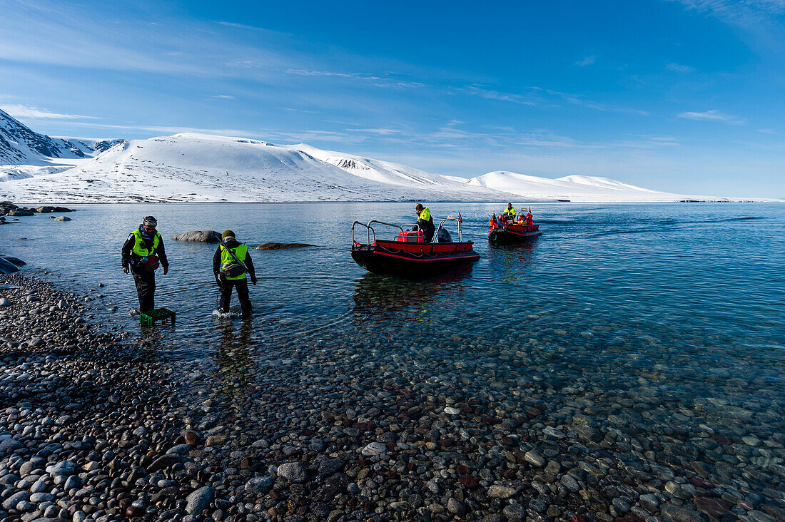 Ecotourists aboard inflatable rafts disembark on Bockfjorden's shore. Bockfjorden, Spitsbergen Island, Svalbard, Norway.