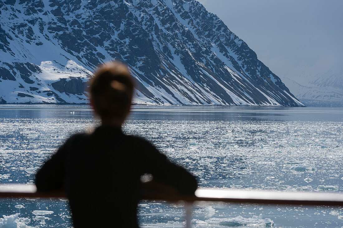 Ein Tourist genießt die Aussicht vom Deck eines Kreuzfahrtschiffs. Spitzbergen, Svalbard, Norwegen