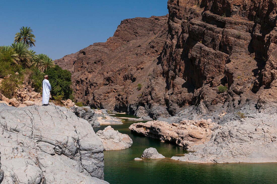 Ein Mann blickt auf einen natürlichen Teich im Wadi Al Arbeieen. Wadi Al Arbeieen, Oman.
