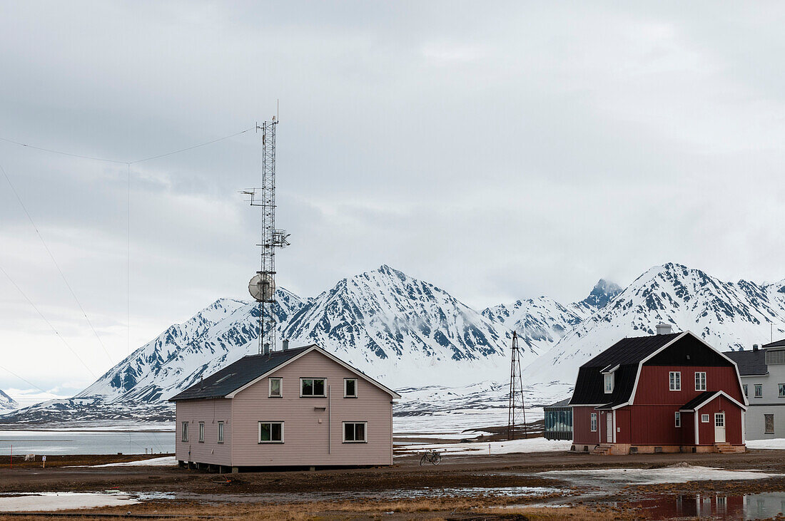 Bunte Gebäude in der Nähe von Bergen und arktischen Gewässern an der Forschungsstation Ny-Alesund. Ny-Alesund, Kongsfjorden, Insel Spitzbergen, Svalbard, Norwegen.