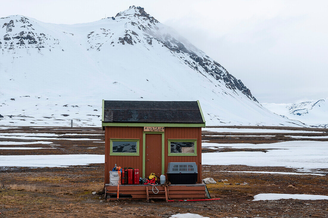 Ein bunt bemaltes Gebäude und Berge an der Forschungsstation, Ny-Alesund. Ny-Alesund, Kongsfjorden, Insel Spitzbergen, Svalbard, Norwegen.