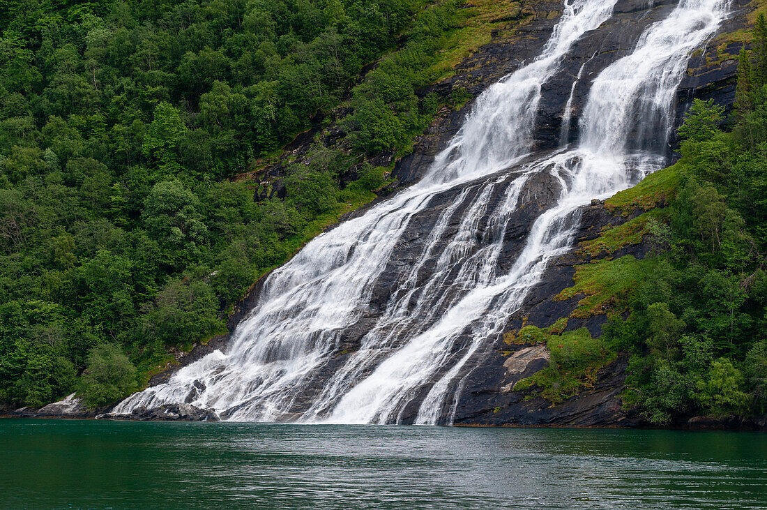 Der Wasserfall Seven Sisters stürzt von steilen Klippen in den Geirangerfjord. Geirangerfjord, Norwegen.