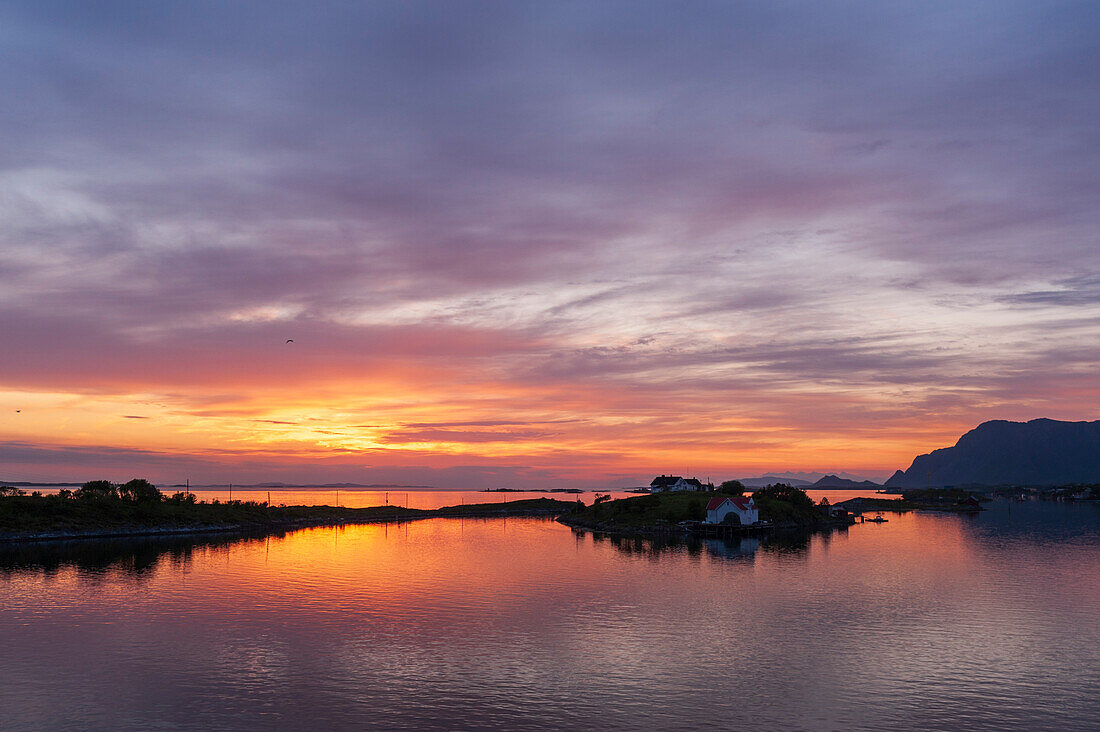 Die Sonne geht hinter den silhouettierten Inseln in der Norwegischen See bei Broennoysund unter. Broennoysund, Bronnoy, Norwegen.