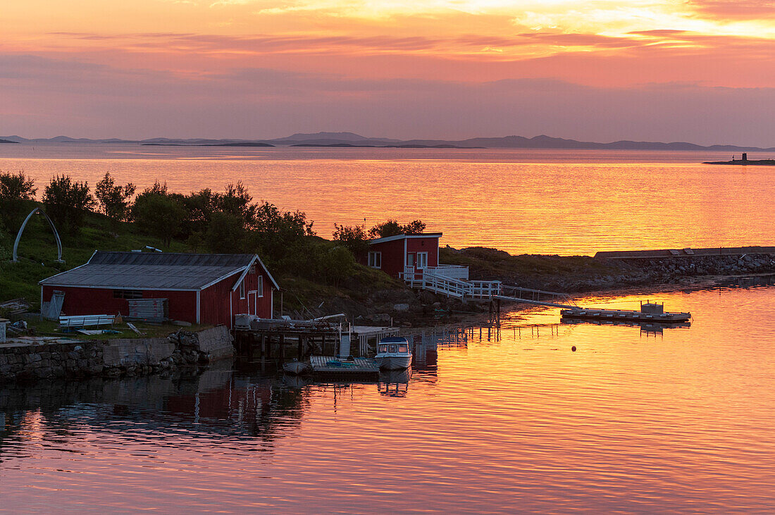 Bootshäuser und Docks in Broennoysund auf ruhigen norwegischen Gewässern, beleuchtet bei Sonnenuntergang. Broennoysund, Bronnoy, Norwegen.