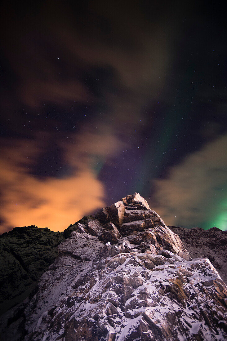 An aurora borealis behind a mountain peak in Andenes. Andenes, Vesteralen Islands, Nordland, Norway.