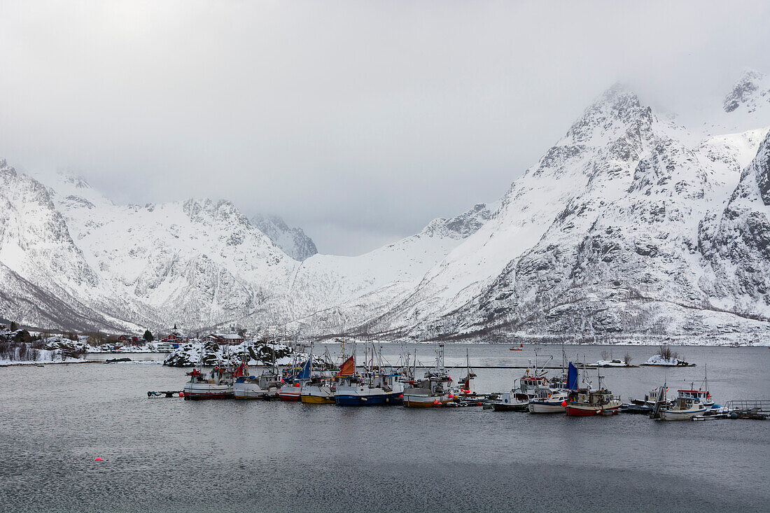 Ein Hafen im Austnes Fjord und schneebedeckte Berge. Austnes Fjord, Lofoten-Inseln, Nordland, Norwegen.