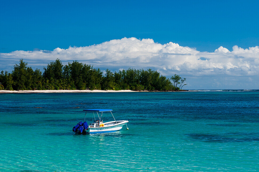 A boat anchored off of a tropical beach in the Indian Ocean. Denis Island, The Republic of the Seychelles.