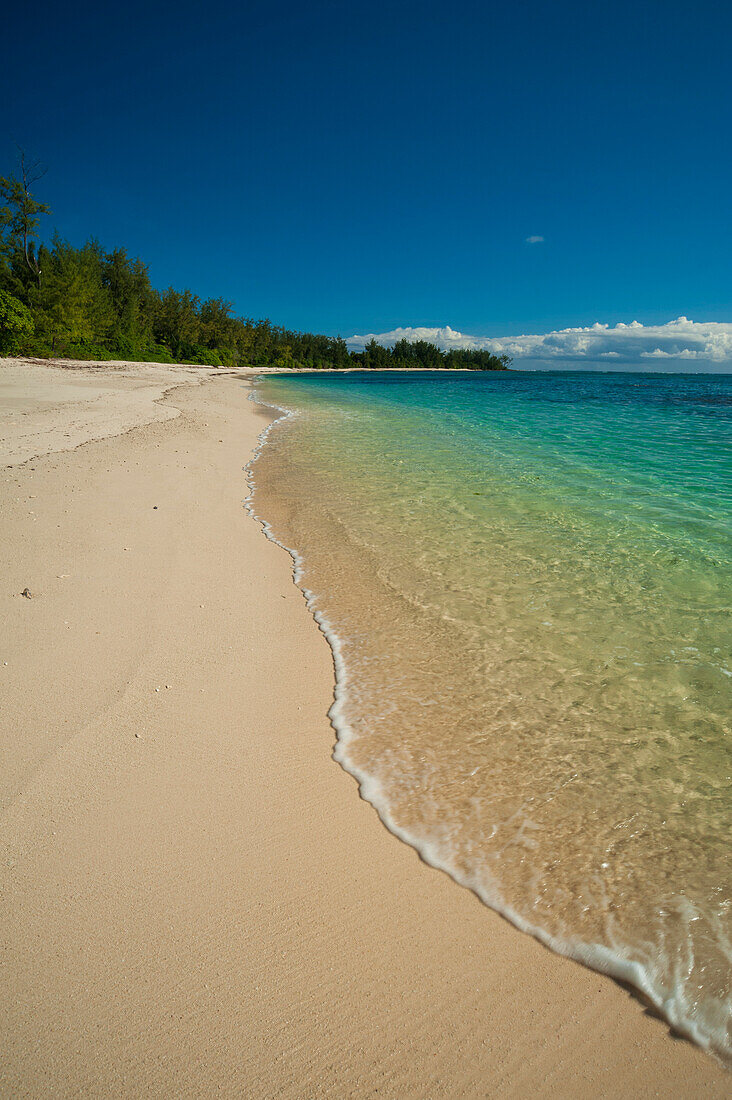 Wasser, das sanft auf einen unberührten, tropischen Sandstrand schwappt. Denis Island, Die Republik der Seychellen.