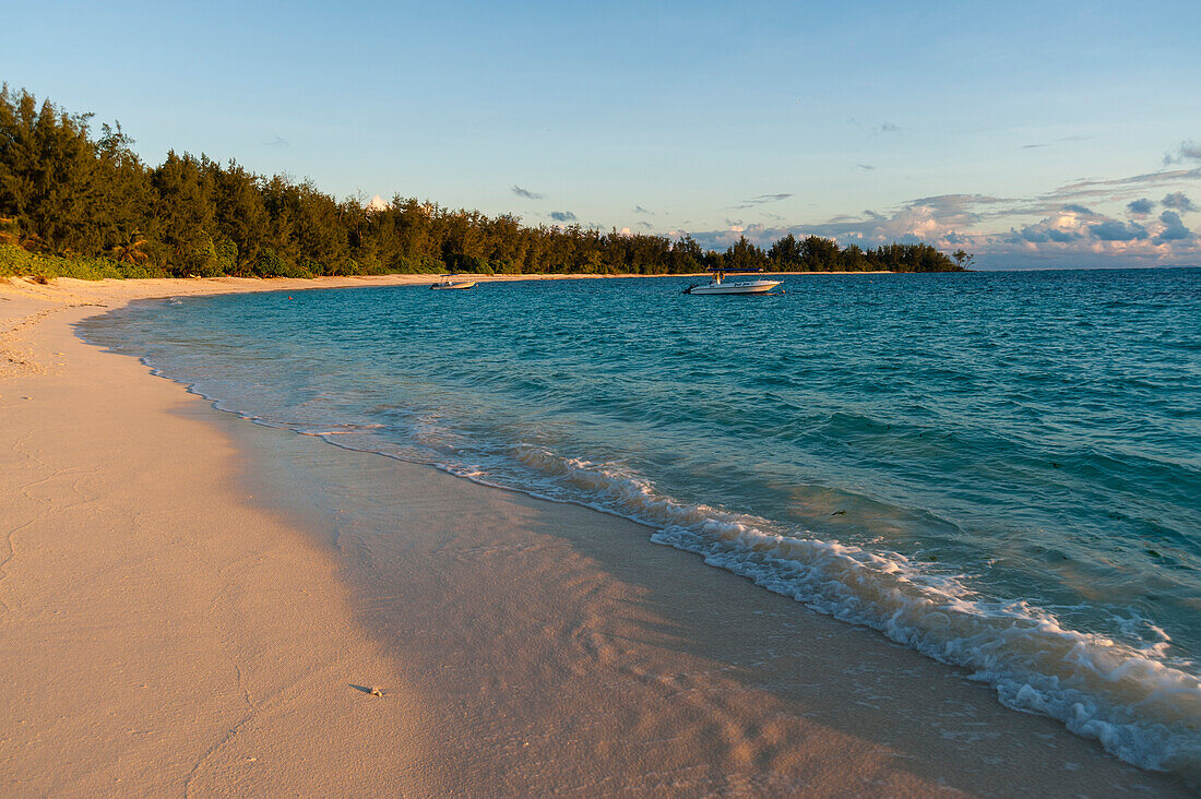 Ein Boot ankert vor der Küste eines tropischen Strandes. Insel Denis, Republik Seychellen.