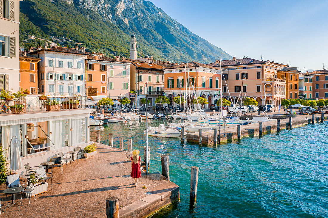 Blonde girl with red dress walking in Gargnano, a small village on Garda Lake, Brescia province, Lombardy, Italy