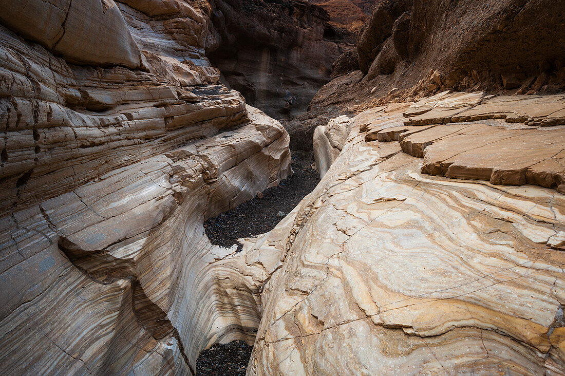 Ein asphaltierter Weg führt durch die glatten, weiß polierten Marmorwände im Mosaic Canyon. Death-Valley-Nationalpark, Kalifornien, USA.