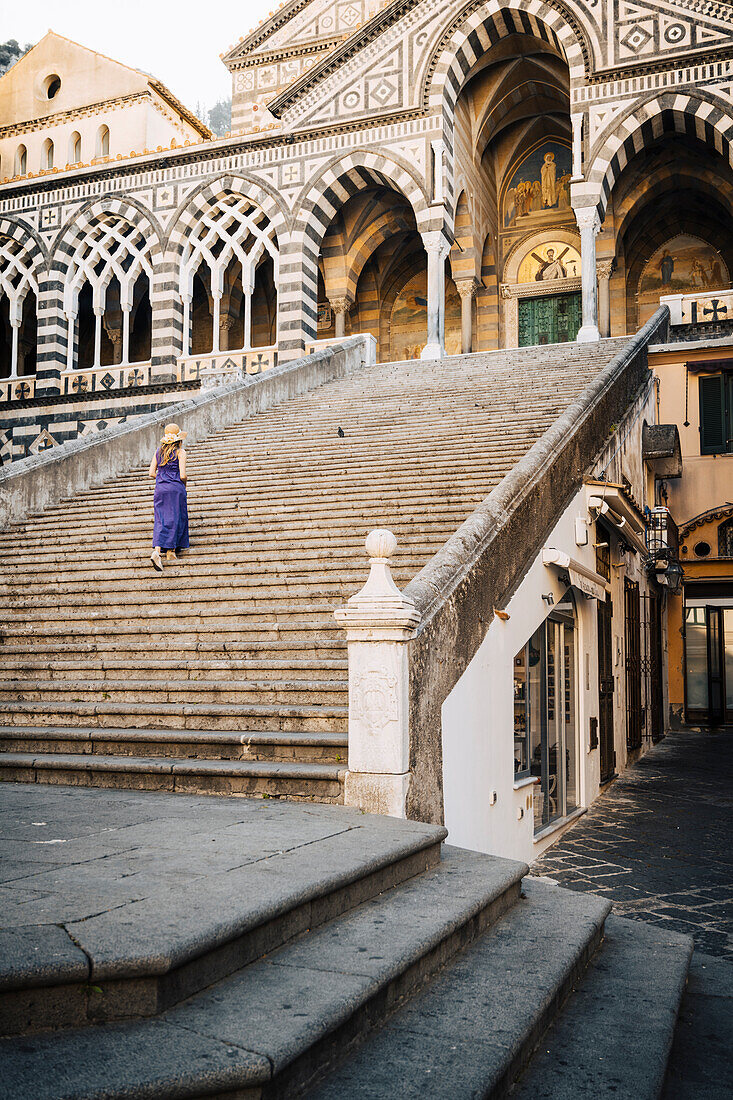 Blondes Mädchen beim Spaziergang in der Kathedrale von Amalfi. Amalfi, Amalfiküste, Provinz Sorrento, Kampanien, Italien.