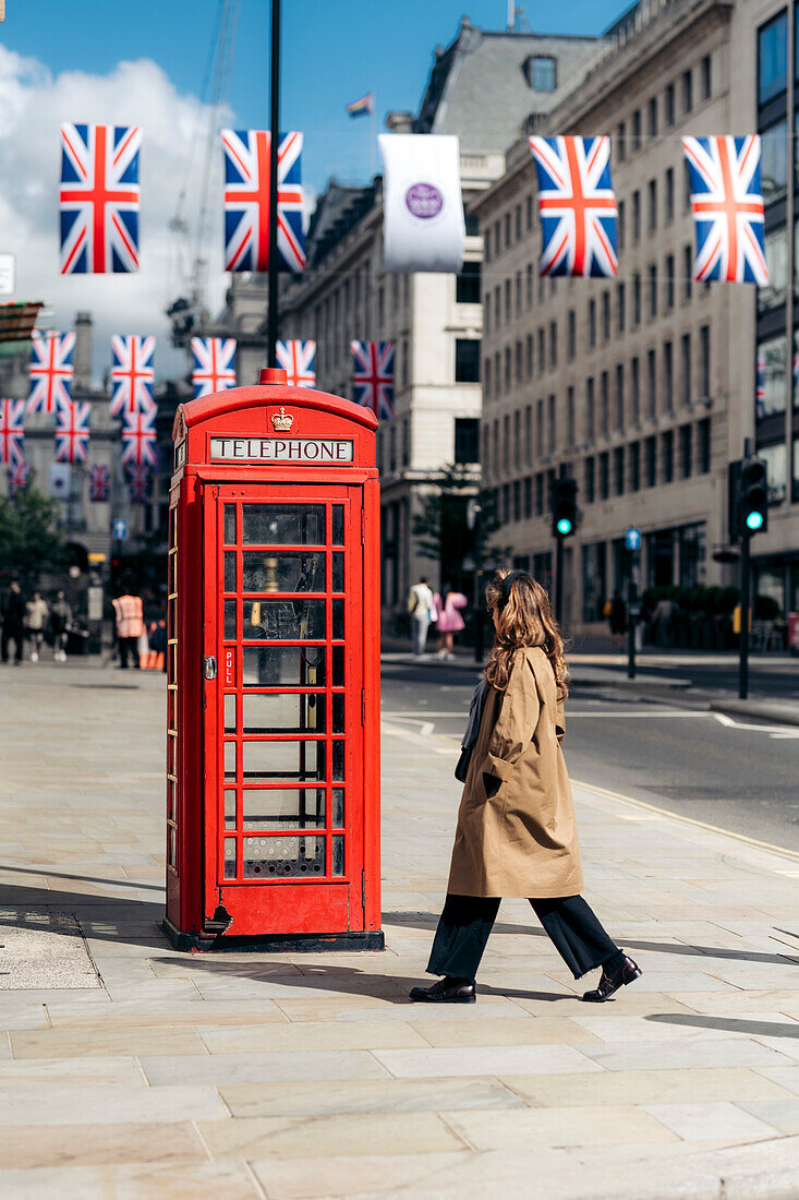 Ein blondes Mädchen zu Fuß zu einer Telefonzelle in 2022 Jubilee gekleidet Straße von London, Vereinigtes Königreich