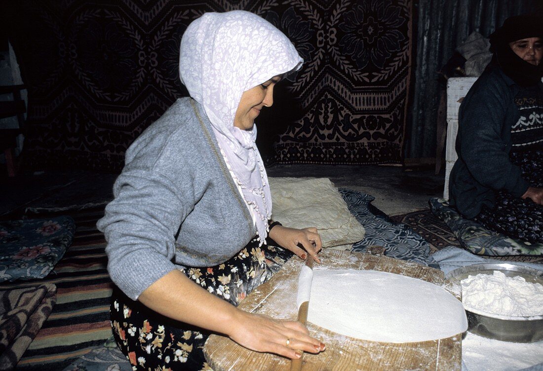 Frau bei Herstellung von Fladenbrot : Teig wird ausgerollt